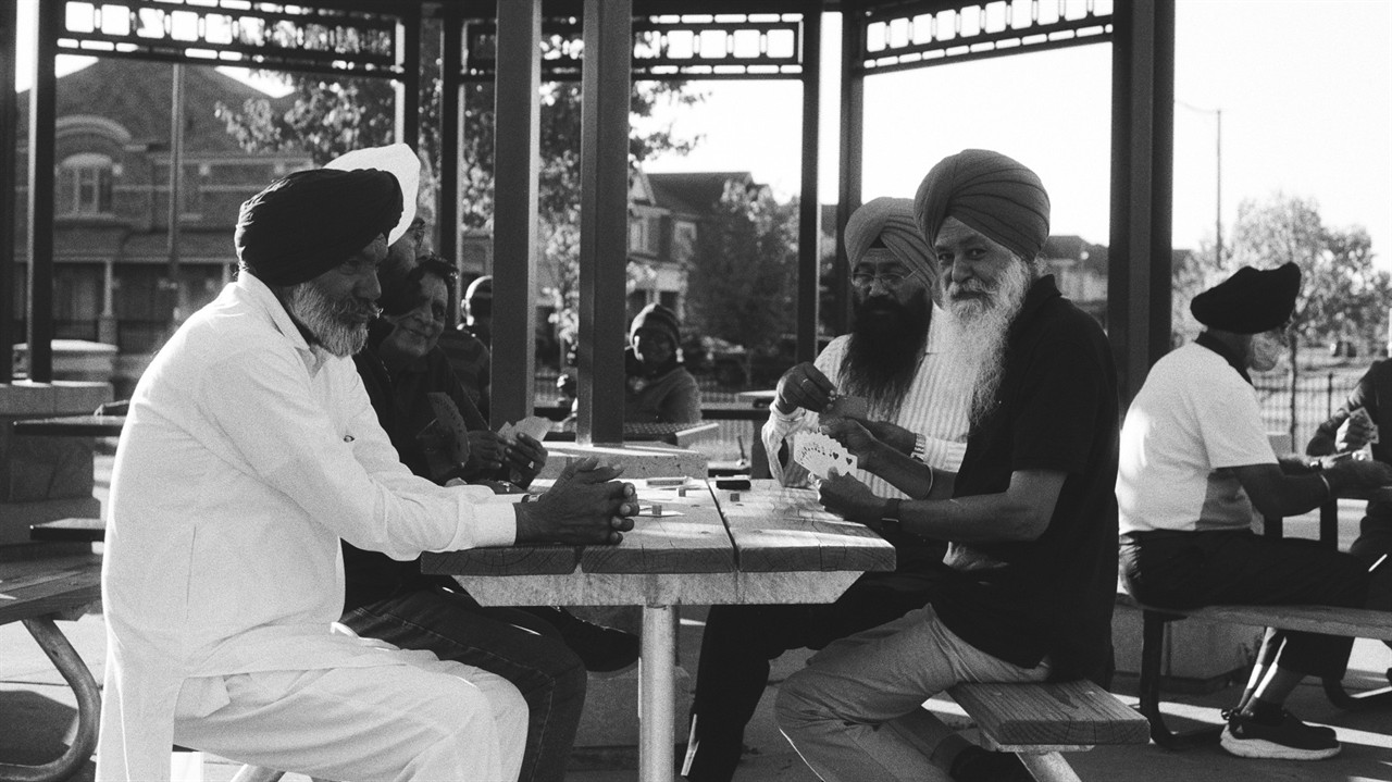Group of sikh men play cards in a park